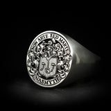 White gold jewellery mens signet ring with hand engraved deep relief heraldic coat of arms for Nasmyth family. Features helmet with hand and mallet crest, shield, mantling and banners with text.