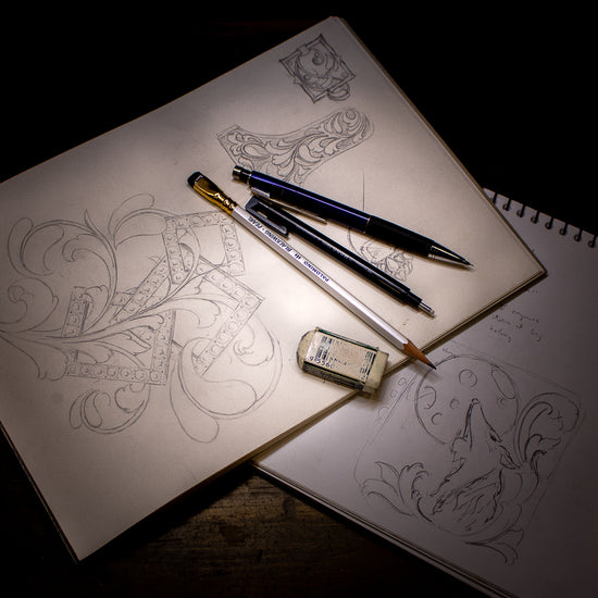 Hand engraving designs in sketch books with pencils and eraser on top