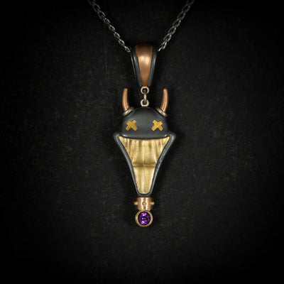 Large Smile Please hand crafted jewellery pendant. Hand crafted smile motif with horns in oxidised silver, 18ct yellow gold, rose gold, white gold and fine gold set with one amethyst. On chain on black background.