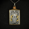 Hand engraved jewellery pendant featuring fantasy scene of a mage deity worshipped in a temple. Made from steel, 24 carat fine gold, 9 carat yellow gold and silver. Set with an orange zircon gemstone. Displayed on black background.