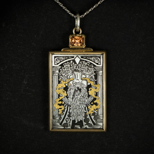 Hand engraved jewellery pendant featuring fantasy scene of a mage deity worshipped in a temple. Made from steel, 24 carat fine gold, 9 carat yellow gold and silver. Set with an orange zircon gemstone. Displayed on black background.